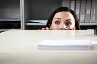 Scared woman hiding in office